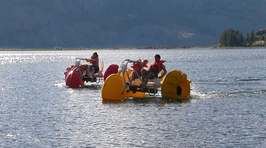 Environmentally friendly yellow and red Aqua-Cycle™ Water Trikes at a lake resort or youth camp Environmentally friendly yellow and red Aqua-Cycle™ Water Trikes at a lake resort or youth camp rented for good profits by a recreational water equipment rental business.